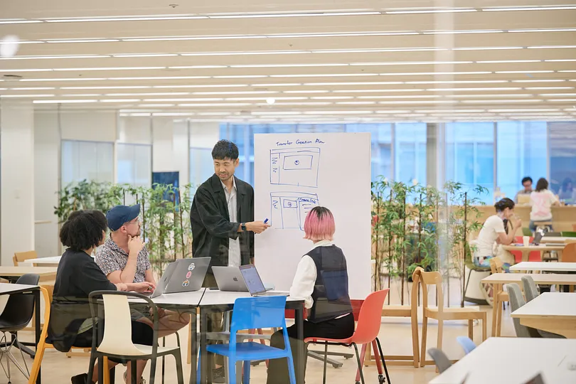A person at a whiteboard discussing a UI with three others