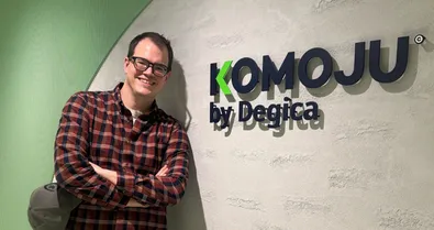 Richard standing next to a KOMOJU by Degica sign.