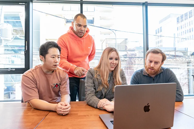 Four people looking at a laptop